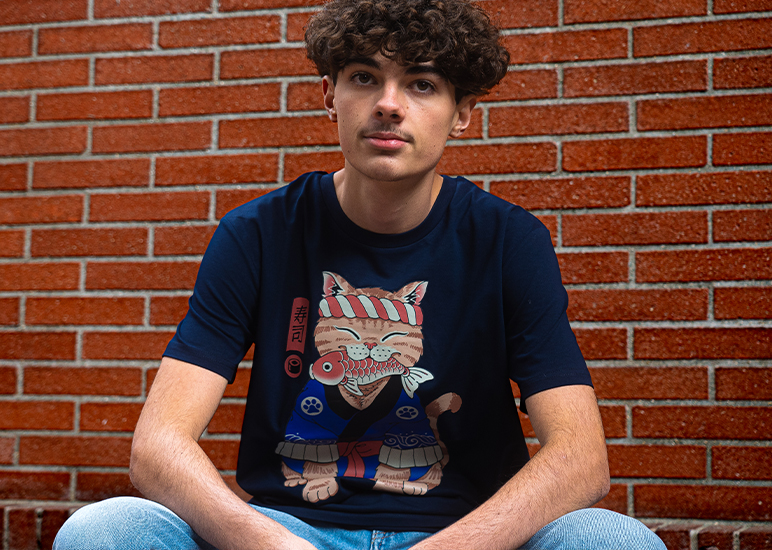 T-shirt chat japonais porté par Tom devant un mur en briques